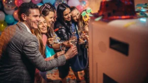 Wedding guests smiling together while posing in front of a photo booth during a celebration.